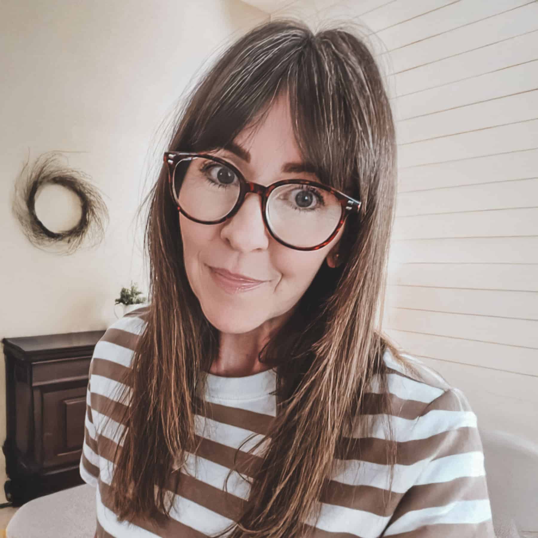 A headshot of Kristine Underwood sitting in her room with her reading glasses on.