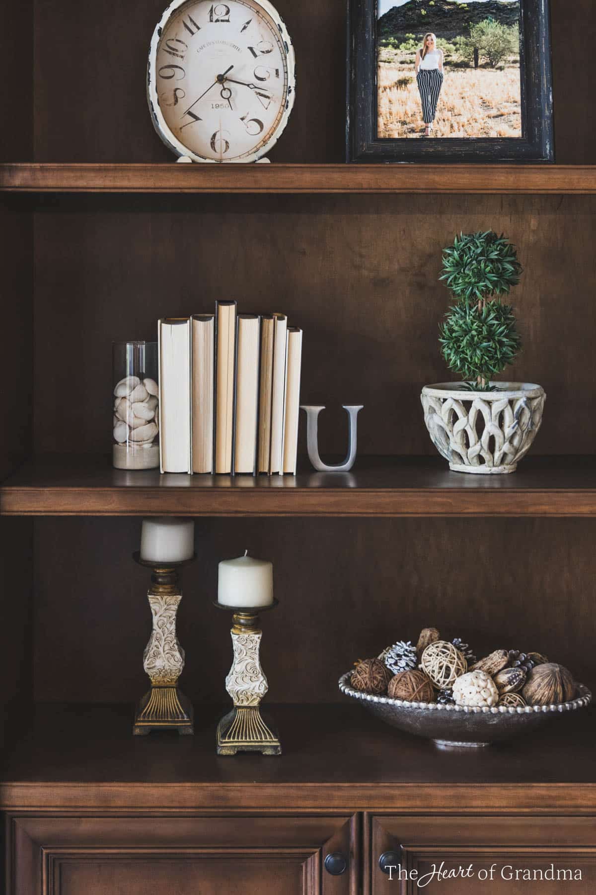 A bookshelf styled with neutral colored decor.