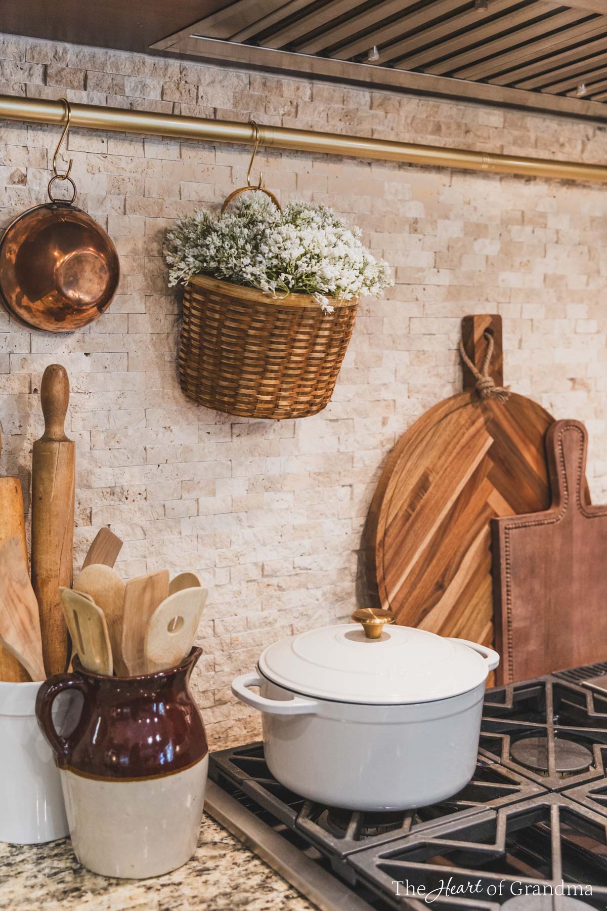 A basket of baby's breath in a tan basket hanging above a stovetop.