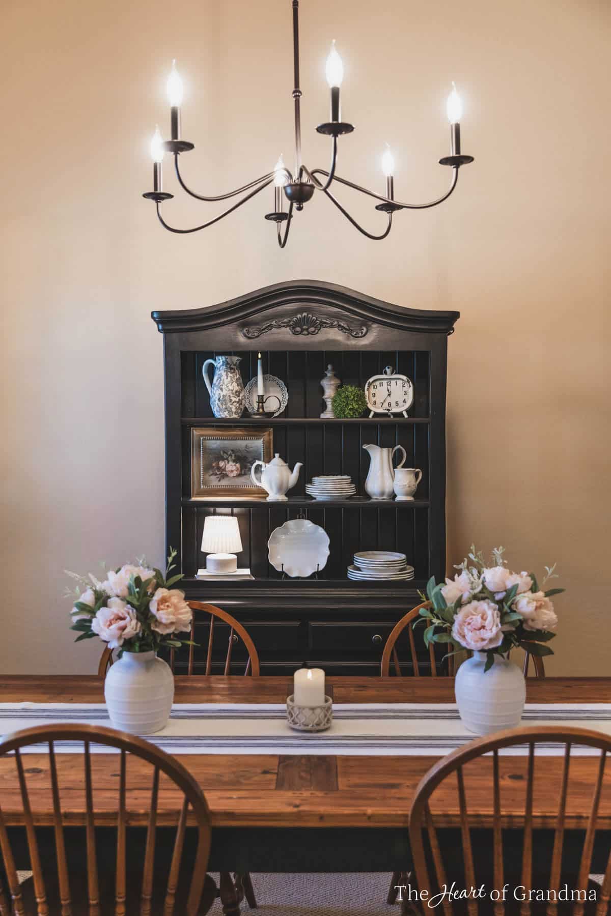 A black china hutch with antique dishes inside.
