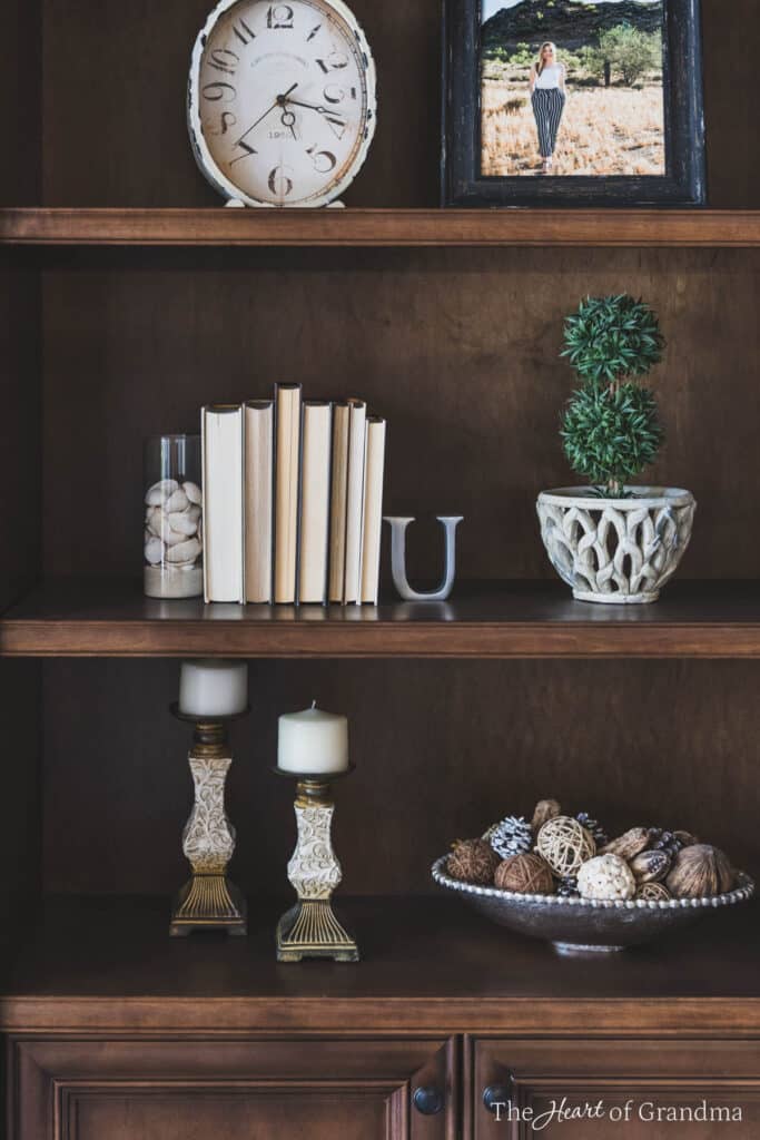 A bookshelf styled with neutral colored decor.