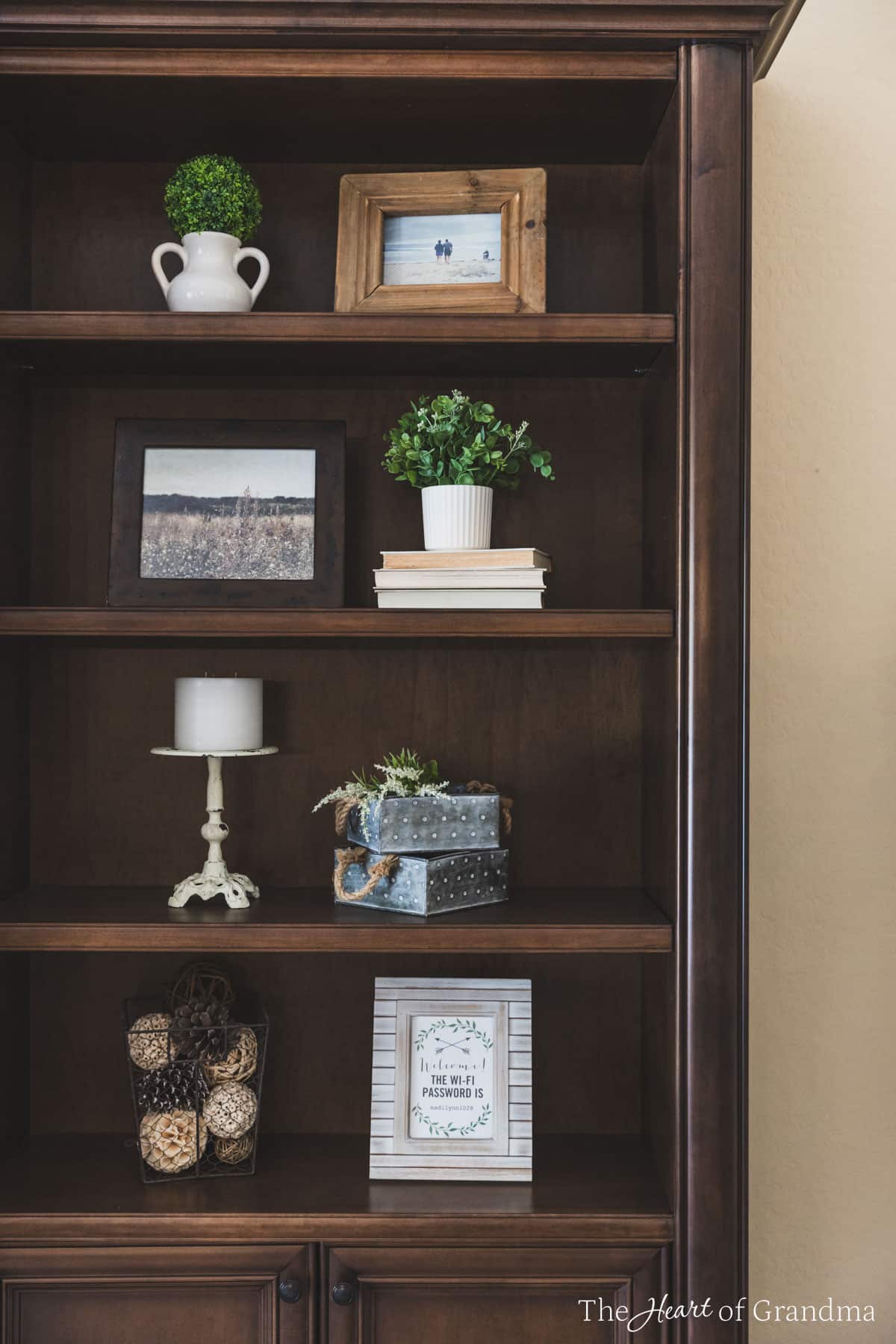 A bookshelf decorated with farmhouse decor, including a stack of old books.