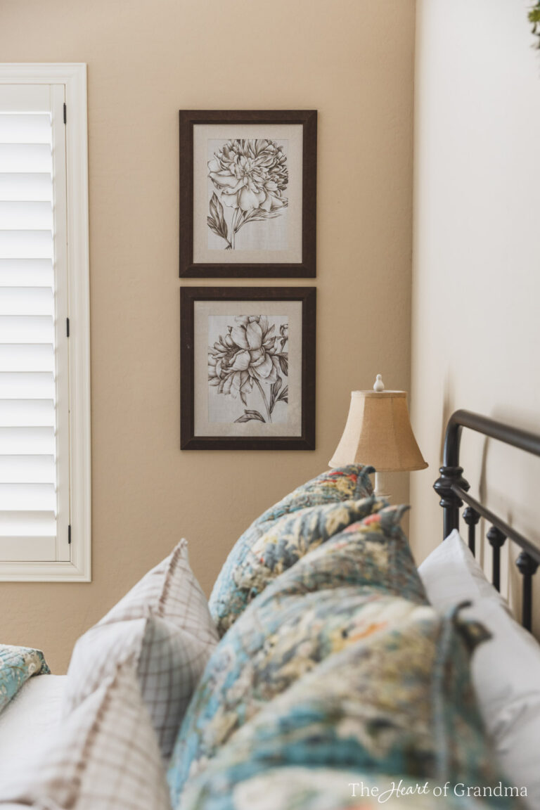 Two pictures hanging on the wall with a made up bed in the foreground.