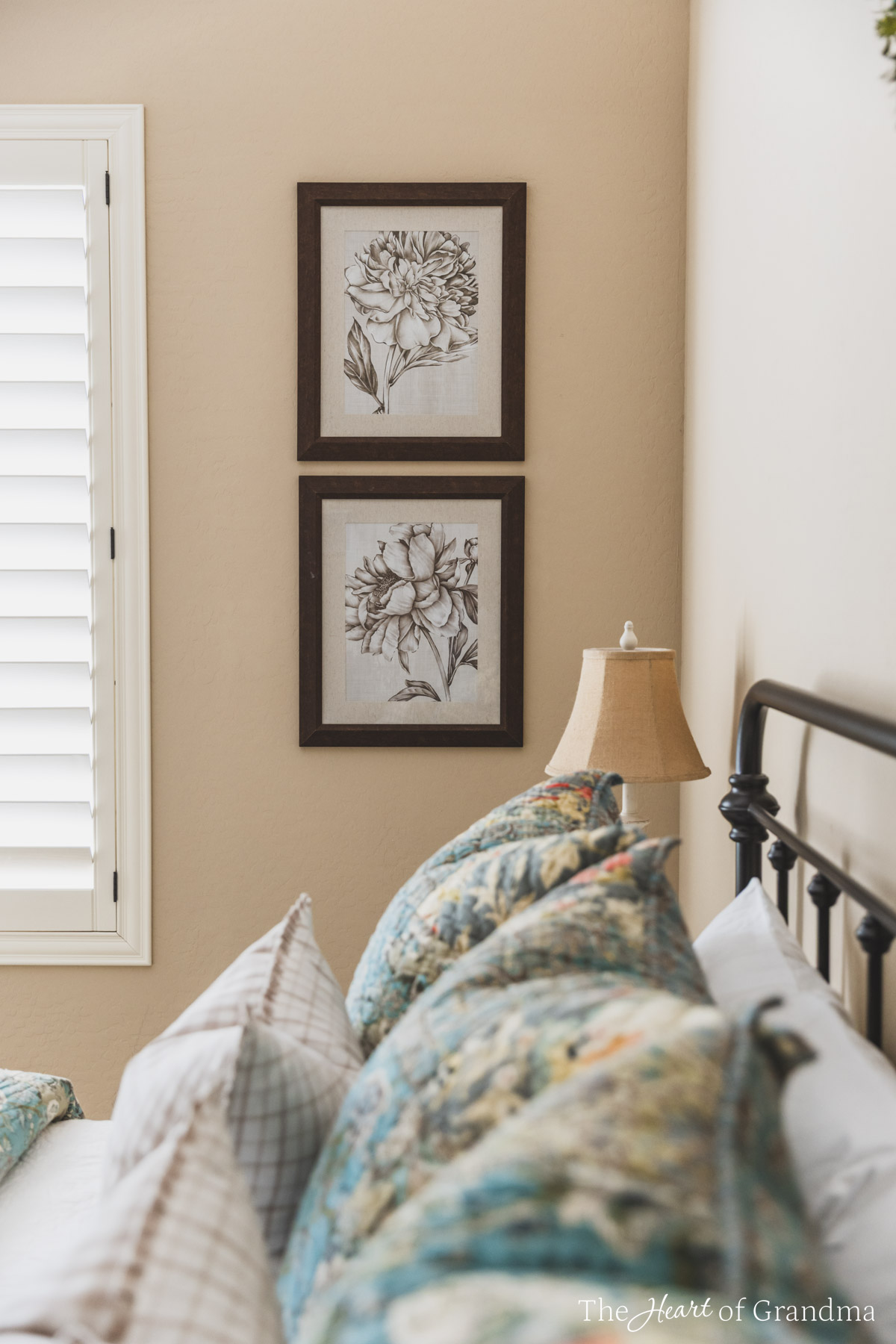 Two pictures hanging on the wall with a made up bed in the foreground.
