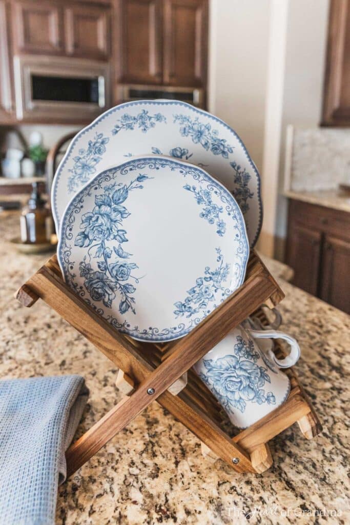 Blue floral dishes in a bamboo dish rack on the counter in a farmhouse kitchen.