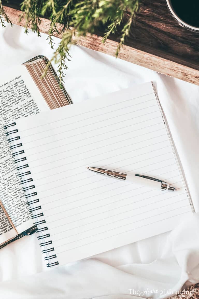An empty note pad with a pen lying on a bed with a tray of coffee.