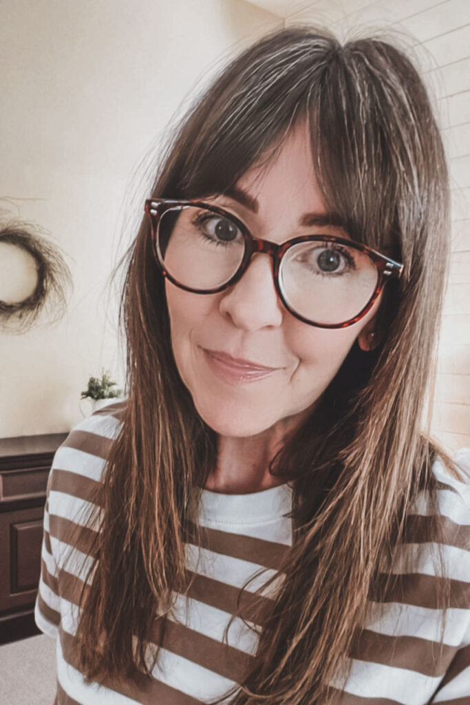 A headshot of Kristine Underwood sitting in her room with her reading glasses on.