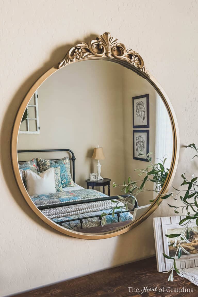 A gold circle mirror reflecting a granny-style bedroom.