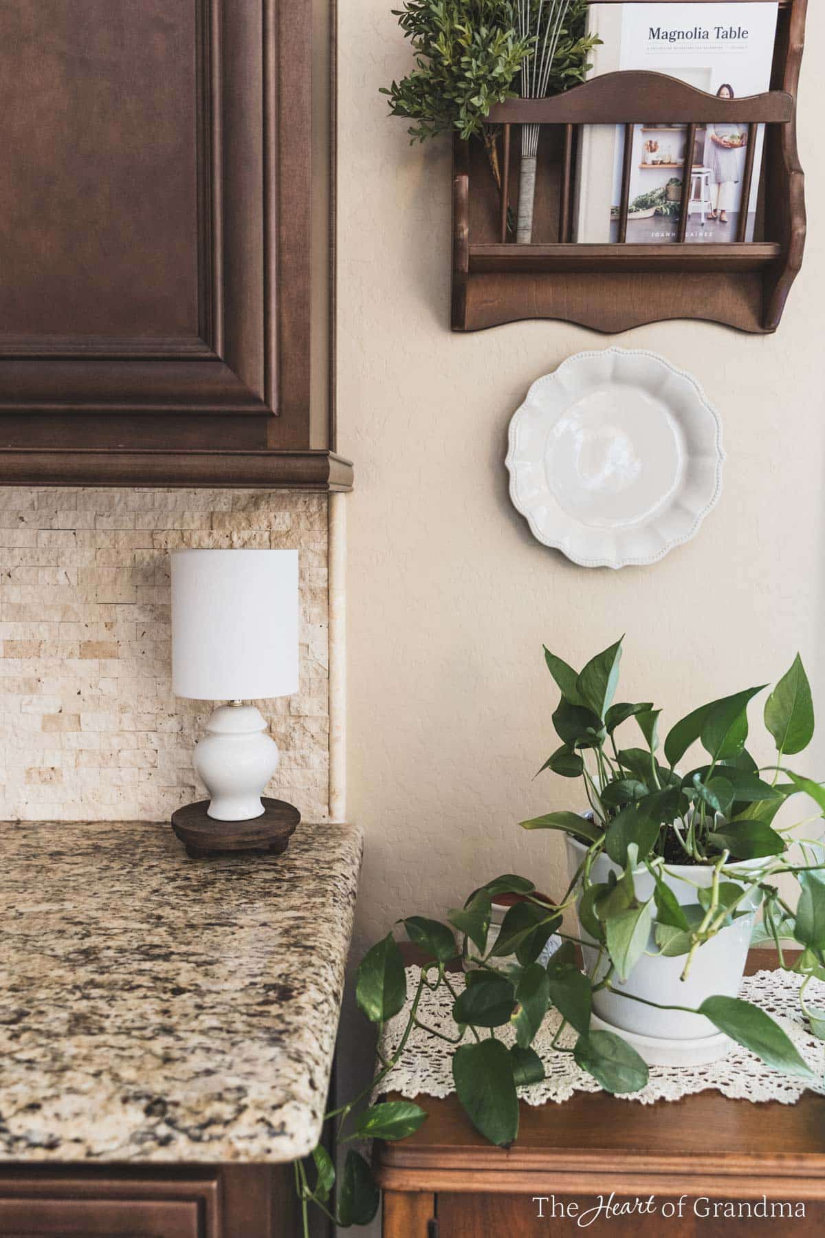 A small lamp on the edge of a kitchen counter next to a table with a green plant.