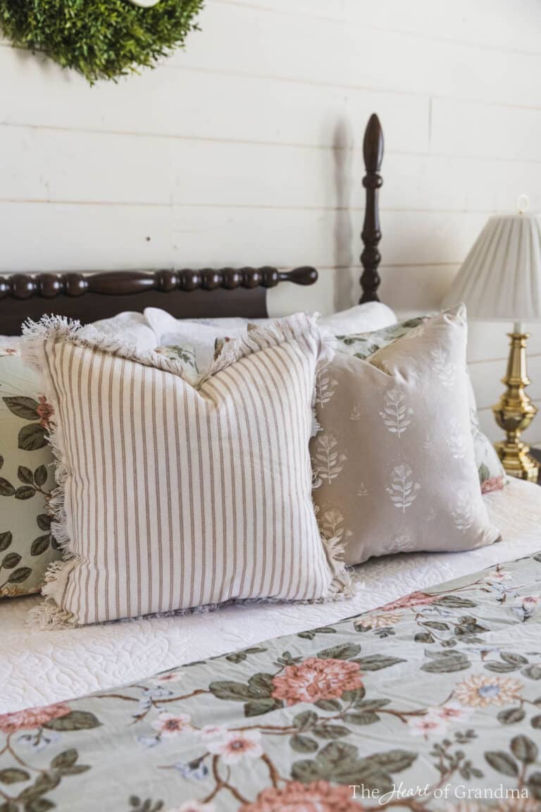 A spindle bed with floral bedding, pinstriped pillows, and a brown accent pillow.