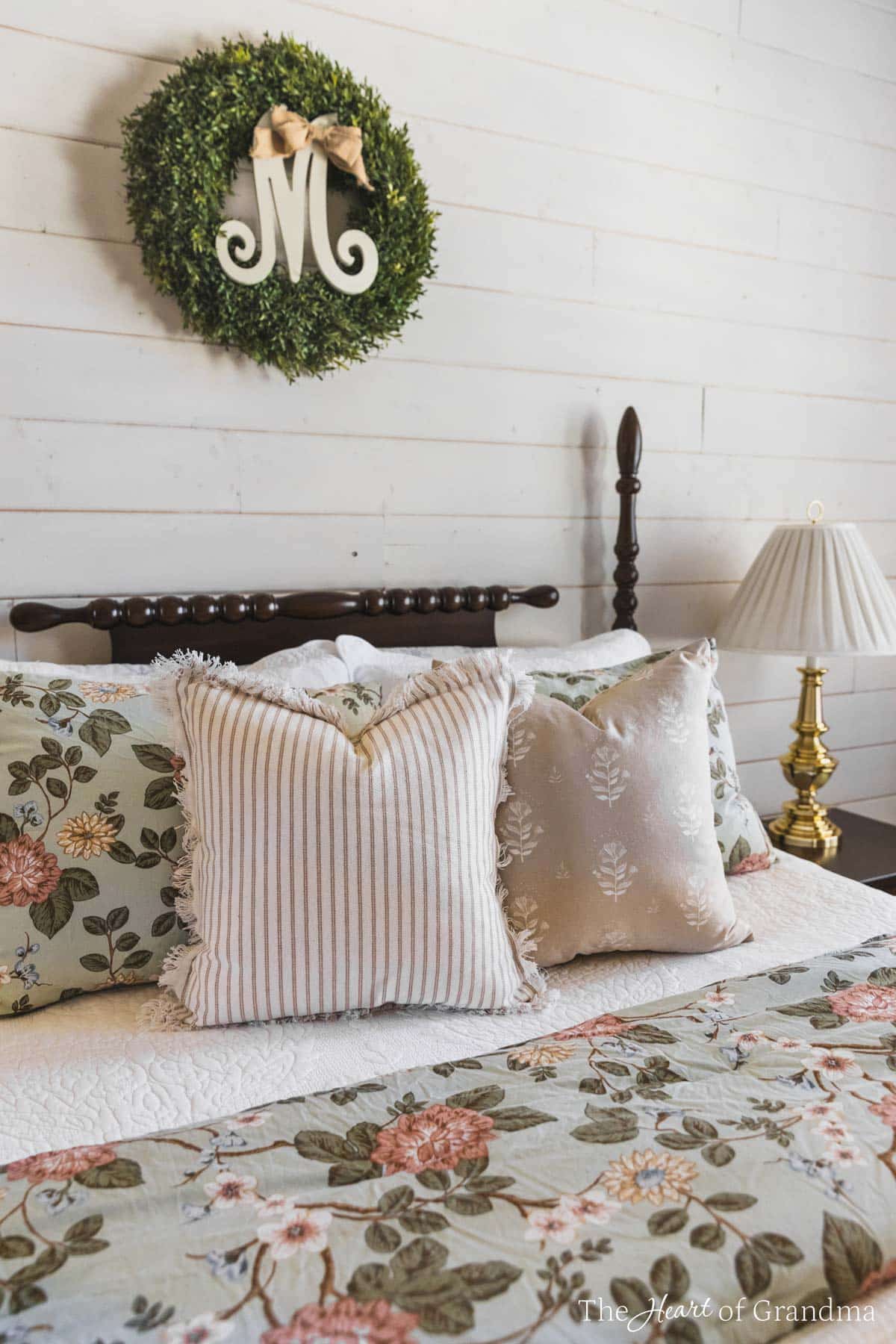 A spindle bed with floral bedding, pinstriped pillows, and a brown accent pillow.