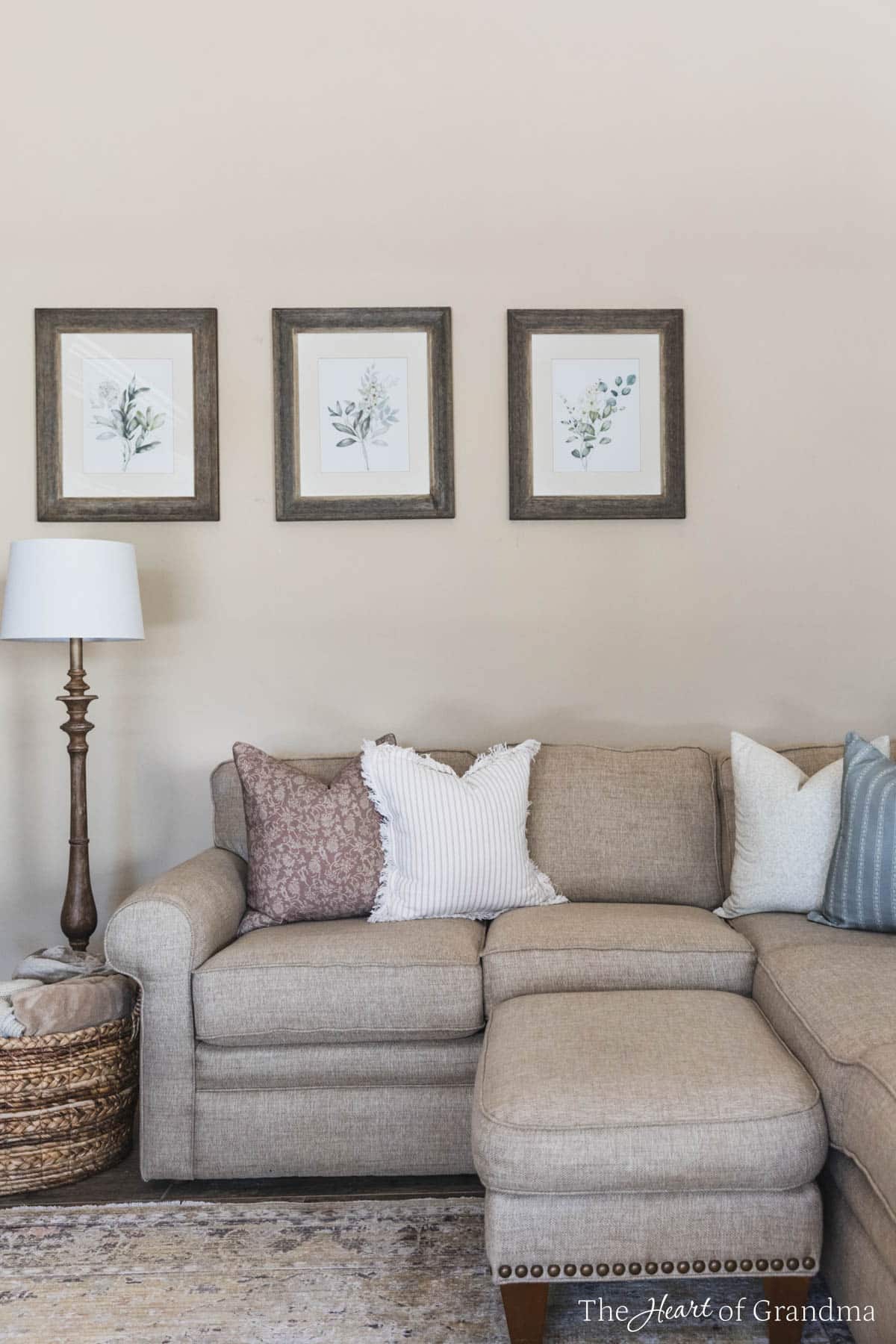 Four coordinating throw pillows on a tan sectional with a lamp standing next to them.