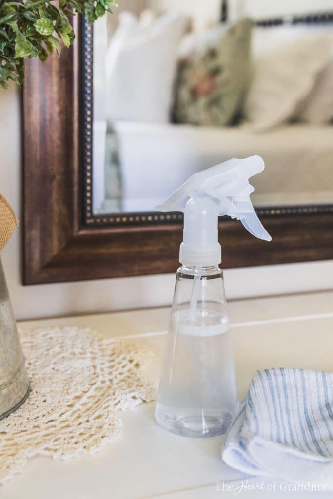 A bottle of old-fashioned glass cleaner sitting in front of a mirror with a blue and white striped cloth.