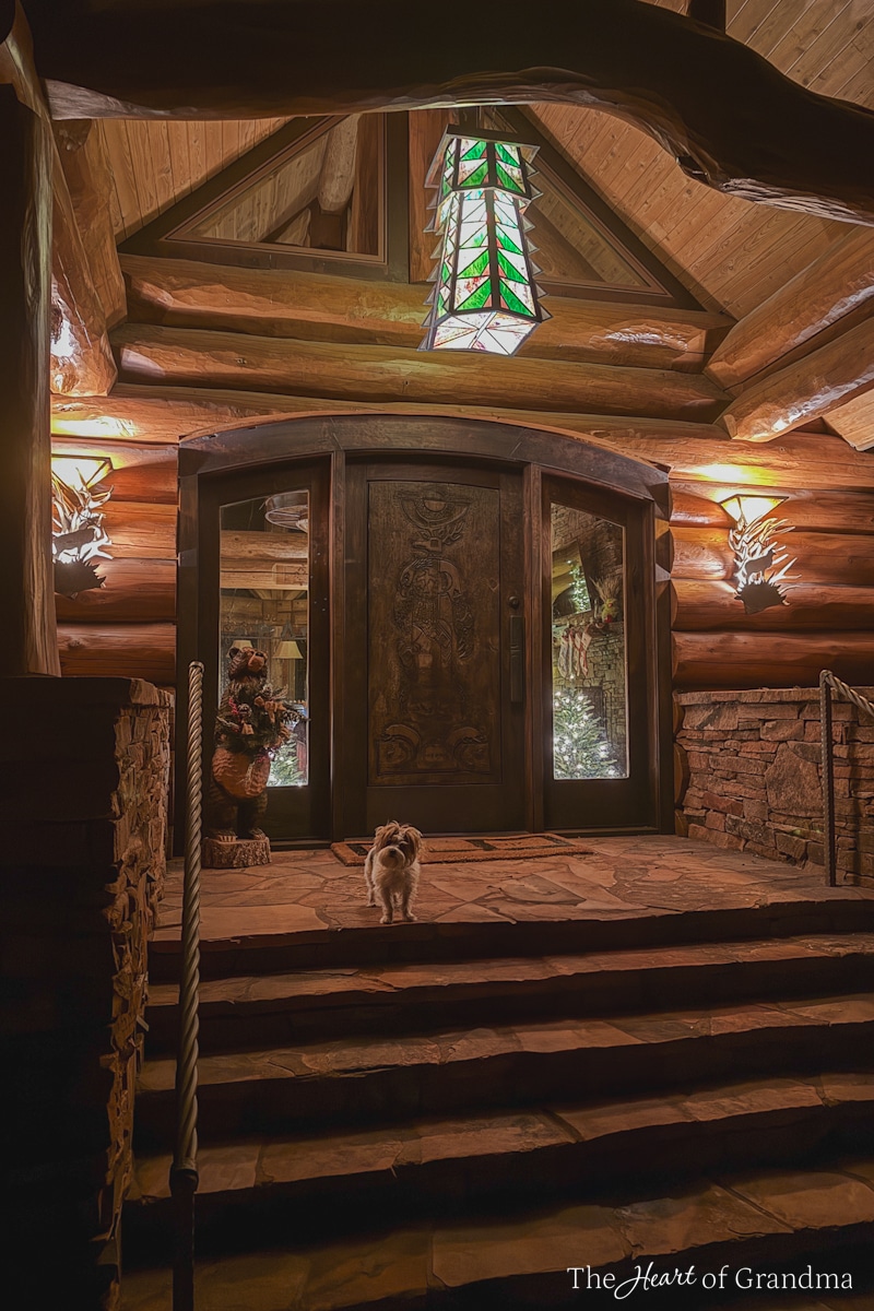A log cabin at dusk with the porch lights on.