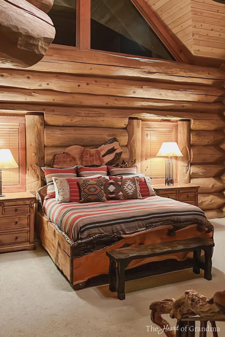 A log cabin bedroom with red striped bedding and southwestern pillows.